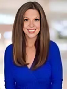 Smiling woman in blue shirt indoors.